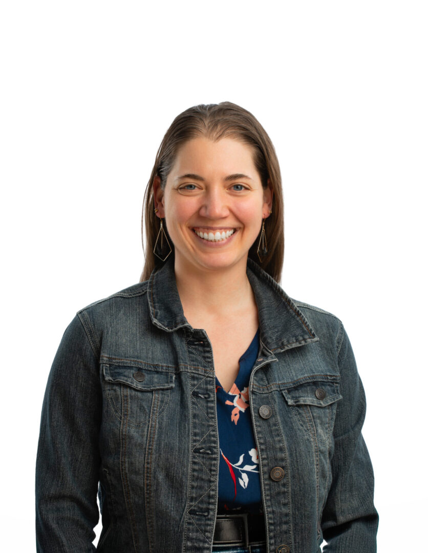 Smiling woman in denim jacket, white background.